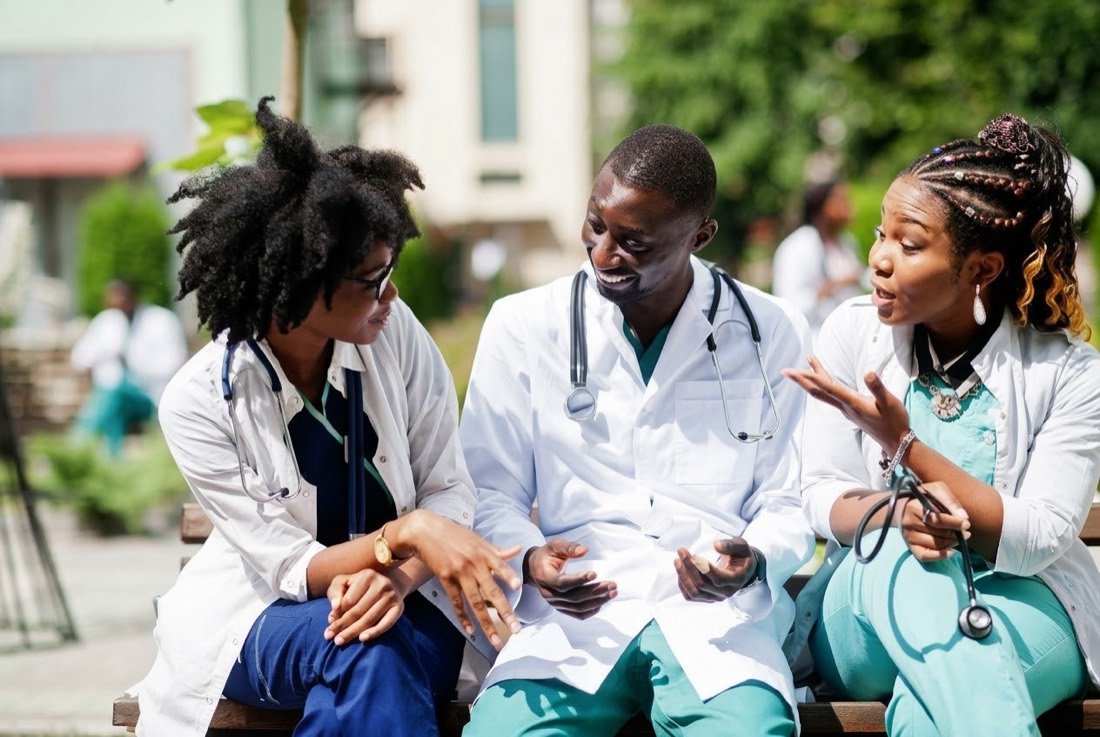 Trois étudiants en médecine en blouse qui discutent sur un banc